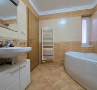 Badezimmer in einer Ferienwohnung mit Badewanne, Waschbecken und Holzboden.