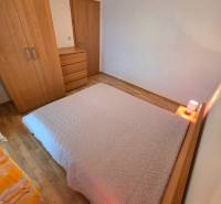 Schlafzimmer in einer Ferienwohnung mit Bett und Möbeln auf einem Boden mit Holzdekor.