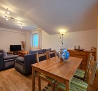 Wohnzimmer in einer Ferienwohnung mit Holzboden, Sofa und Esstisch.