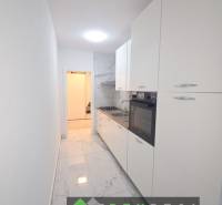 Schmale weiße Küche mit Kochfeld und Ofen, Marmorboden in einer 3-Zimmer-Wohnung.