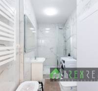 Badezimmer mit Duschkabine, Waschmaschine und Marmormauer in einer 3-Zimmer-Wohnung.