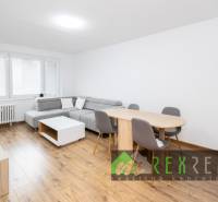 Wohnzimmer in einer 3-Zimmer-Wohnung mit Holzboden, grauem Sofa und Esstisch.