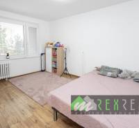 Helles Schlafzimmer in einer 3-Zimmer-Wohnung mit Holzboden und rosa Teppich.