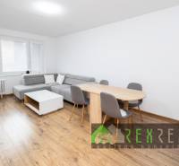 Wohnzimmer mit Ecksofa, Esstisch und Boden in Holzoptik.