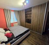 Schlafzimmer in einer 3-Zimmer-Wohnung mit einem großen Schrank und einem Boden in Holzoptik.