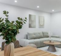 Wohnbereich einer 3-Zimmer-Wohnung mit Sofa, Tisch und Blumen in hellen Farbtönen.