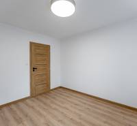 Ein Zimmer mit einem Holzboden und Holztüren in einer 3-Zimmer-Wohnung.