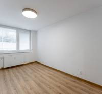 Ein leerer Raum mit einem großen Fenster, weißen Wänden und einem Boden in Holzoptik in einer 3-Zimmer-Wohnung.