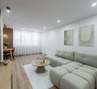 Wohnzimmer einer 3-Zimmer-Wohnung mit bequemer Couch und Boden in Holzoptik.