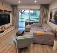 Wohnzimmer in einem Einfamilienhaus mit Holzdekorboden, Ecksofa und Fernseher.