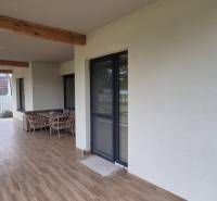 Die Terrasse des Einfamilienhauses in Studienka mit einer Schaukel und Möbeln, Boden mit Holzdekor.