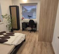 Schlafzimmer mit Bett, Tisch und Holzboden in einem Einfamilienhaus.