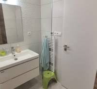 Badezimmer in einem Einfamilienhaus mit Waschbecken, Relief-Fliesen, Spiegel und beleuchteten Wänden.