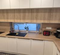 Küche in einem Einfamilienhaus mit weißen Schränken und einer Arbeitsplatte in Holzoptik.