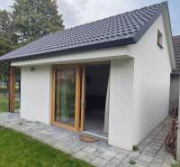 Ein Einfamilienhaus in Studienka mit weißer Fassade und schrägem Dach, umrahmt von grünen Bäumen.