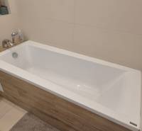Ein Badezimmer mit einer mit Holzdekor verkleideten Badewanne in einem Einfamilienhaus.