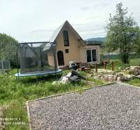 Eine Hütte in Hliník nad Hronom mit einem Trampolin und einem steinigen Weg im Garten.