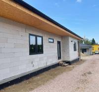 Ein Einfamilienhaus in Radava im Bau mit ungedämmter Fassade und einer Schotterstraße.