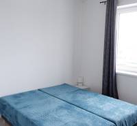 Schlafzimmer in einem Einfamilienhaus mit blauen Überwürfen auf dem Bett und Jalousien.