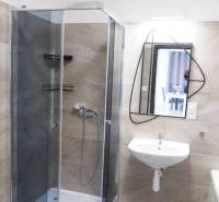 Ein Badezimmer in einem Einfamilienhaus mit einer Eckdusche und einem unkonventionellen Spiegel.