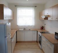 Küche in einem Einfamilienhaus mit weißen Schränken und einem Boden in Holzoptik.