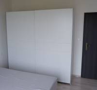 Ein Zimmer in einem Einfamilienhaus mit einem Bett, einem weißen Schrank und einer dunklen Tür.