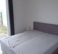 Ein Schlafzimmer in einem Einfamilienhaus mit einem Bett und großen bodentiefen Fenstern mit Holzdekor.