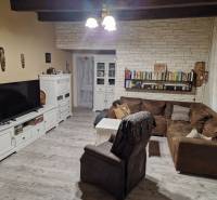 Wohnzimmer mit Ecksofa, weißen Möbeln und Boden in Holzoptik in einem Einfamilienhaus.