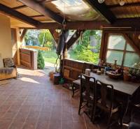 Rustikale Terrasse eines Einfamilienhauses mit Holzmöbeln und Blick auf den Garten.