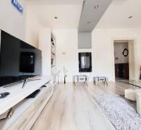 Wohnzimmer in einem Einfamilienhaus mit Fernseher und Holzboden.