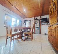 Esszimmer in einem Einfamilienhaus mit Holzbalkendecke und Fliesenboden.