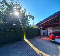 Ein Einfamilienhaus in Neded mit einem roten Auto vor der Garage, ein sonniger Tag und ein Baum.