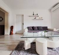 Wohnzimmer in einem Einfamilienhaus mit Sofa, Glastisch und Boden in Holzoptik.