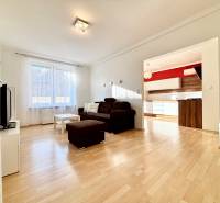 Wohnzimmer in einer Zweizimmerwohnung mit braunem Sofa und Boden in Holzoptik.