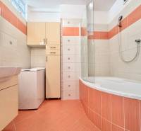 Badezimmer in einer 2-Zimmer-Wohnung mit Badewanne, Waschmaschine und Stauraum.