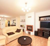 Wohnzimmer in einem Einfamilienhaus mit Kamin, Ledersofas und einem Boden in Holzoptik.