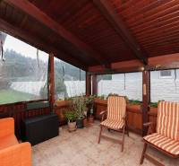 Wintergarten eines Einfamilienhauses mit Stühlen und Pflanzen, Boden mit Fliesen.