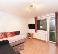 Wohnzimmer in einem Einfamilienhaus mit Sofa, Fernseher und Boden in Holzoptik.