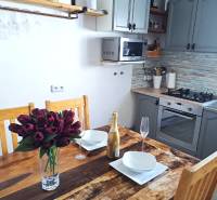 Küche in einem Einfamilienhaus mit Holztisch, Blumen, Champagner und Küchenzeile.