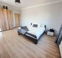 Schlafzimmer in einem Einfamilienhaus mit Bett, Kleiderschrank und Boden mit Holzdekor.