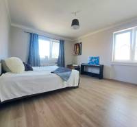 Ein Zimmer mit einem Bett, zwei Fenstern, einem Klavier und einem Boden mit Holzdekor in einem Einfamilienhaus.