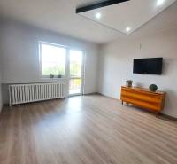 Wohnzimmer in einem Einfamilienhaus mit Holzboden, Fernseher und Kommode.