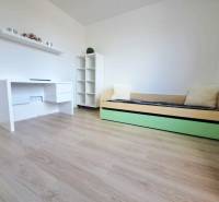 Ein Zimmer in einem Einfamilienhaus mit einem weißen Tisch, einem Bett und einem Boden mit Holzdekor.