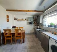 Küche in einem Einfamilienhaus mit Holzbalkendecke und einer Reihe von Holzstühlen.