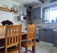 Küche in einem Einfamilienhaus mit Holztisch, Stühlen und grauen Schränken.