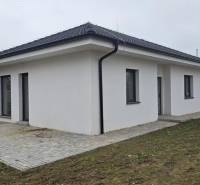 Ein Einfamilienhaus in Cífer mit einem Schrägdach und einer gepflasterten Terrasse im Garten.