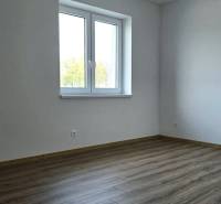 Ein Zimmer in einem Einfamilienhaus mit einem Boden in Holzoptik und weißen Wänden.