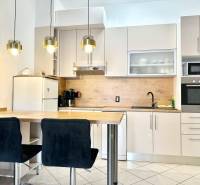 Küche in einer Ferienwohnung mit Bartresen, Hängeleuchten und weißem Schrank.