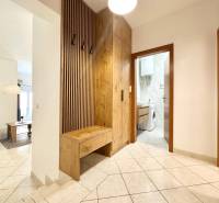 Flur eines Ferienapartments mit Waschmaschine und Garderobenwand in Holzoptik.