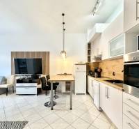 Innenraum eines Ferienapartments mit Küchenzeile, Esstisch und Fernseher an der Wand.